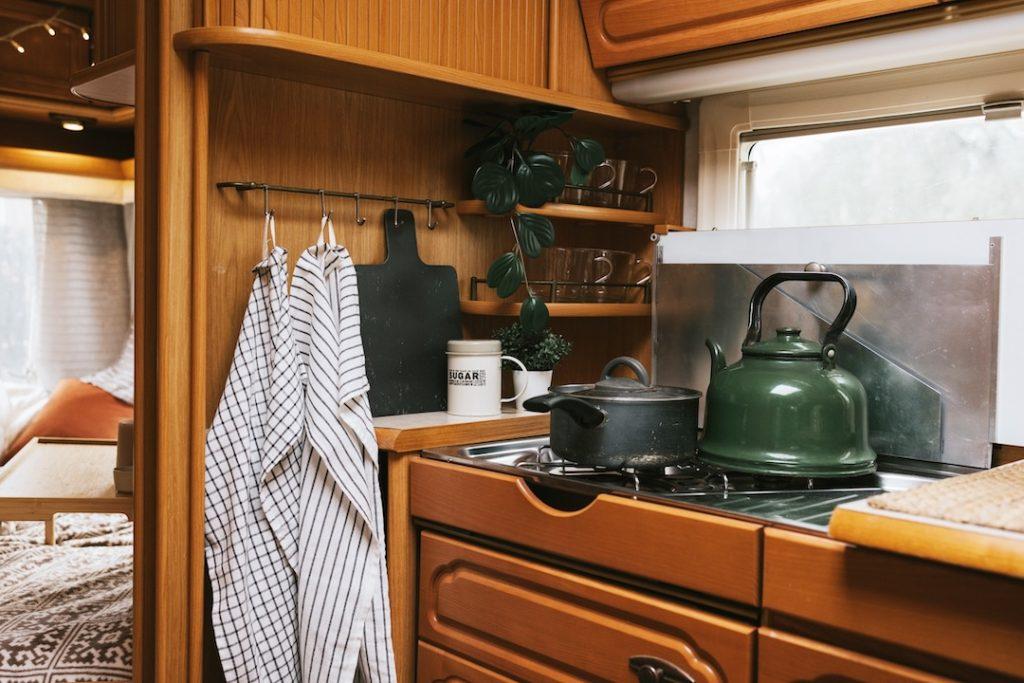 Photo of cozy RV kitchen with stove and oven setup.