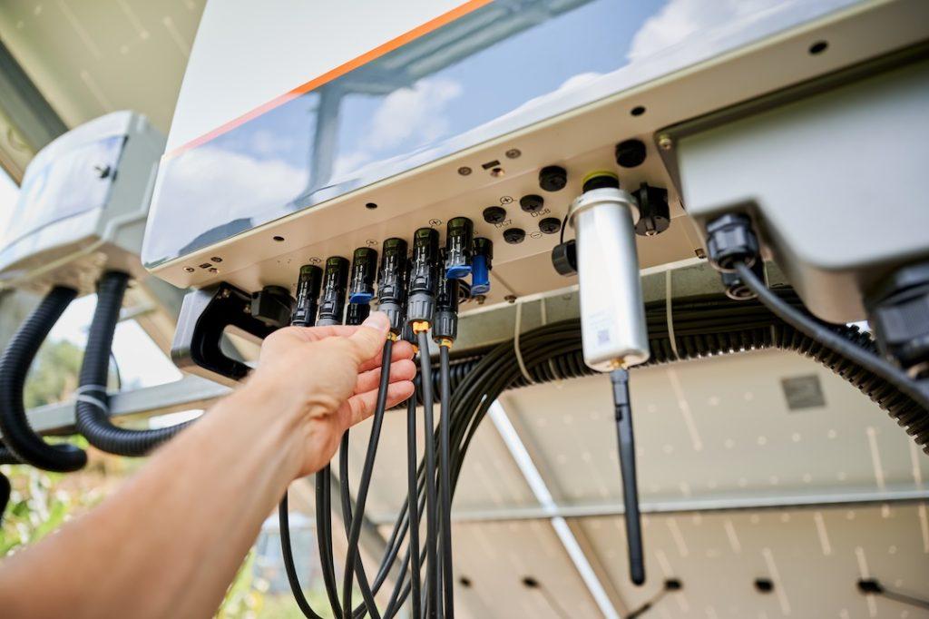 Professional worker connecting wires to solar inverter. Pov of configuring inverter. Male worker turning on PV battery. SSUCv3H4sIAAAAAAAACnRSO2+DMBDeK/U/IM9Bghhc6N6hQ6UO3aoOfhxgxbEj2ySKovz32hhaD+3GfXf+HnfcHh+KAjHqJEfPxS1WoZZKzc5b6qXRAa52K25BC7A5craYVDlAZV6BkN5YSVUOMur5pOkRAqhnpSJ8X5rIeepnBy56WSFOPYyBI4E/FMnwZ6qLrbE0w4vQQq9axBBRfJd13cxi991cwBZUi+JFgx2vaBtJsv9wfkBwbpQJ839wvknHQSmqwczulzB9fP1saATNr0vCLLkFBTQlX0OhoWdDI7AoMWNN2VRDW1KCeSkqxjqBOWm7blFJ1Ohw8WCP+e7oLKTJ1nY2nKo4gDPlk5Vc6jF7Zvy0XHl7xs2svY2W0RYbKWNOlKl4wyFwwoZP1LkwLjY8E+LhHOaY6Wjjl8ArKxLh1LGsMd43fVV1fffUtDWp8TqQfo9JBp7FzkYUan6QIo8uowPUACcE+L6EuhvKph+g7MV+KOsWM4JZ1QtBwgrv3wAAAP//AwDkxVyMBwMAAA==
