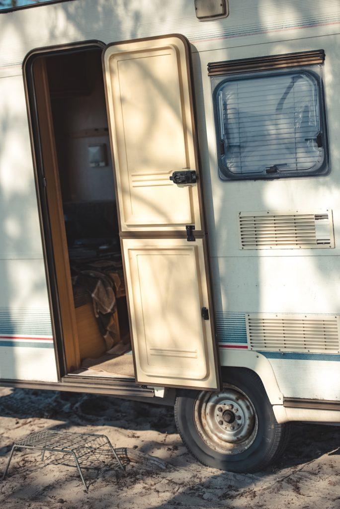 close up of travel trailer with open door in camp